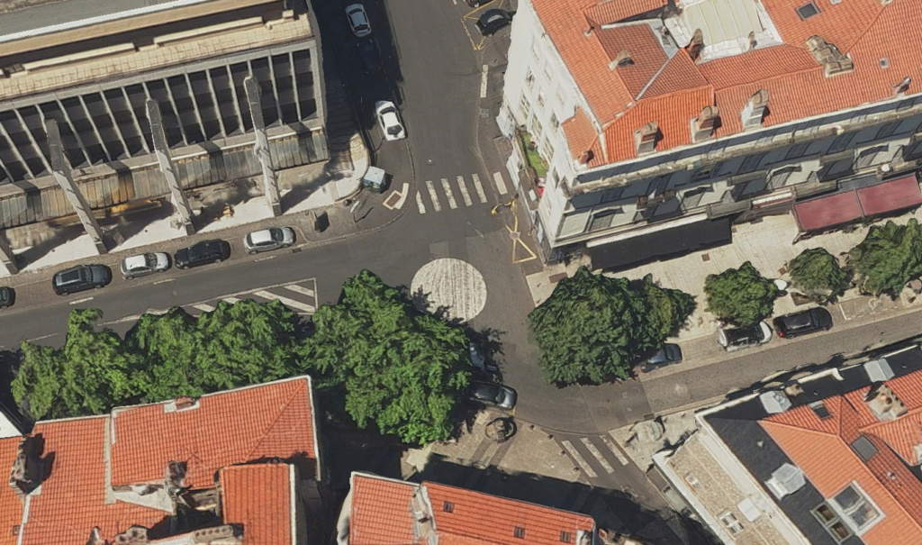  vue 3D aérienne d’un carrefour urbain. Au sol, un rond de peinture blanche de plus de 2 mètres de diamètre matérialise le giratoire. Des arbres, des voitures, et des bâtiments entourent de près le carrefour.